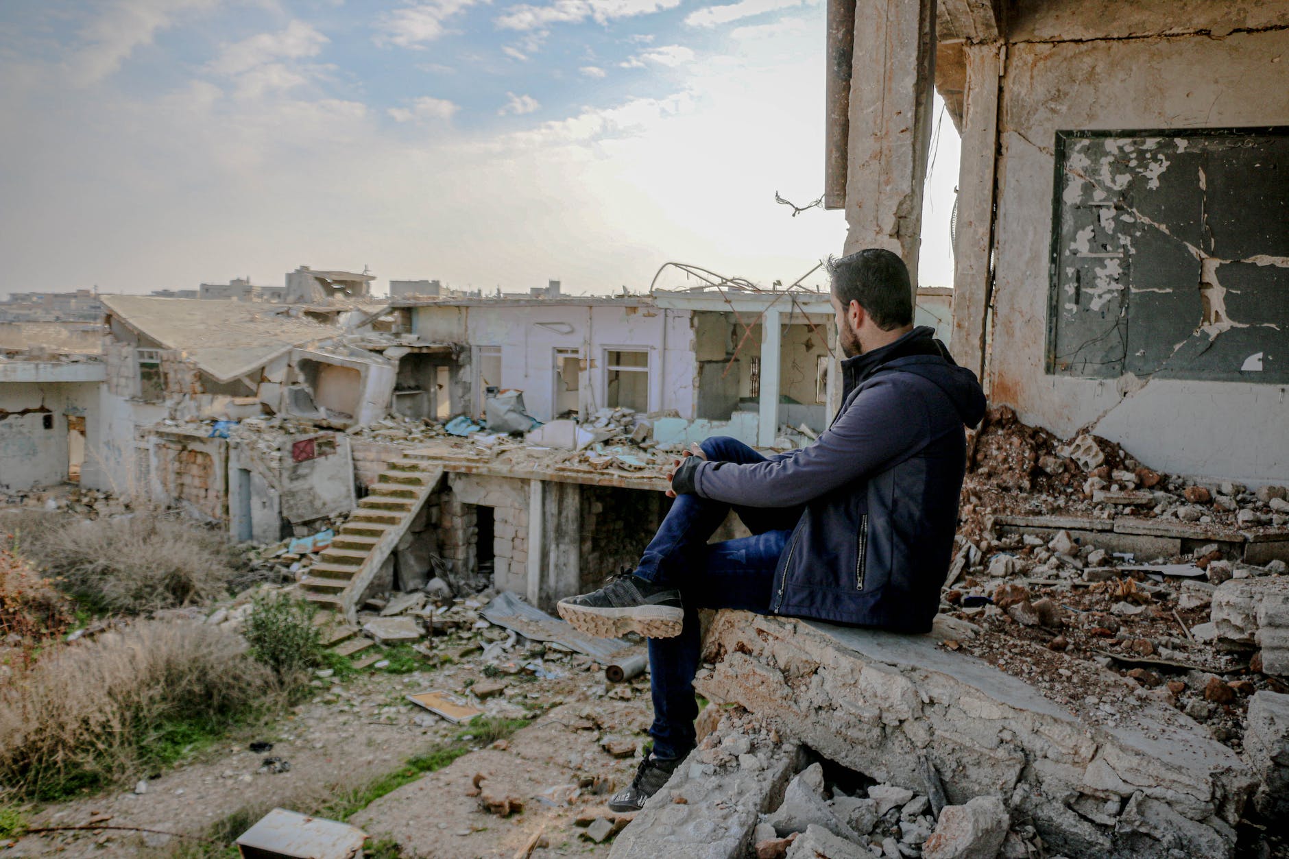 unrecognizable man sitting on damaged ruins of building
